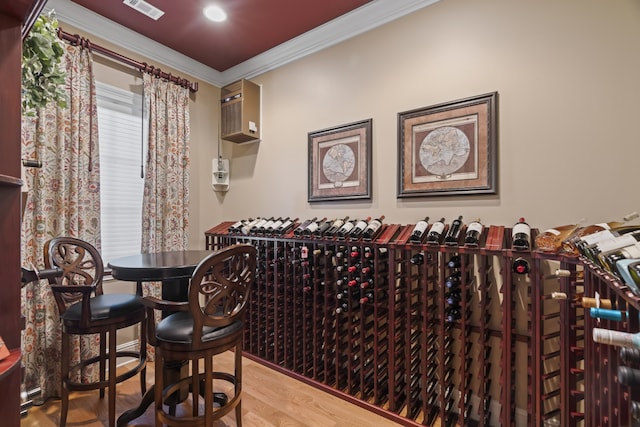 wine room with wood-type flooring, an AC wall unit, and crown molding