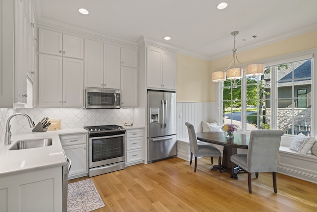 kitchen featuring light hardwood / wood-style flooring, backsplash, white cabinetry, appliances with stainless steel finishes, and sink