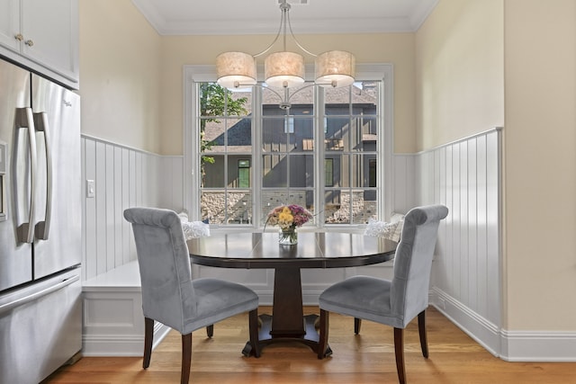 dining space with a notable chandelier, light wood-type flooring, and crown molding