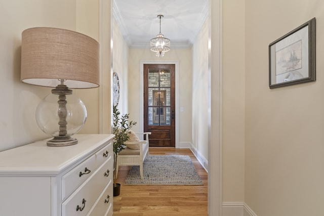 entrance foyer featuring light hardwood / wood-style floors, crown molding, and a notable chandelier