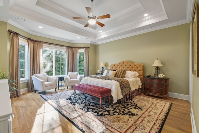 bedroom featuring ceiling fan, a tray ceiling, hardwood / wood-style flooring, and ornamental molding