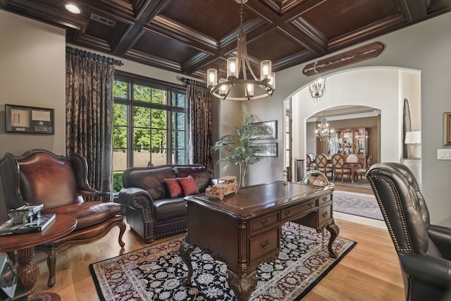 interior space with light hardwood / wood-style floors, ornamental molding, an inviting chandelier, beamed ceiling, and coffered ceiling