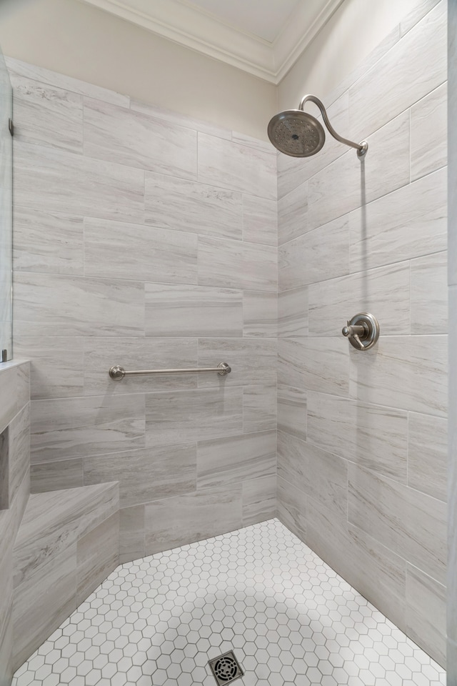 bathroom with ornamental molding and tiled shower