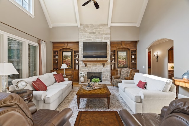 living room featuring built in shelves, beam ceiling, a stone fireplace, high vaulted ceiling, and ceiling fan