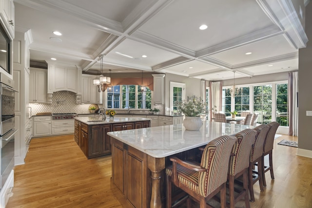 kitchen featuring coffered ceiling, a healthy amount of sunlight, and a spacious island