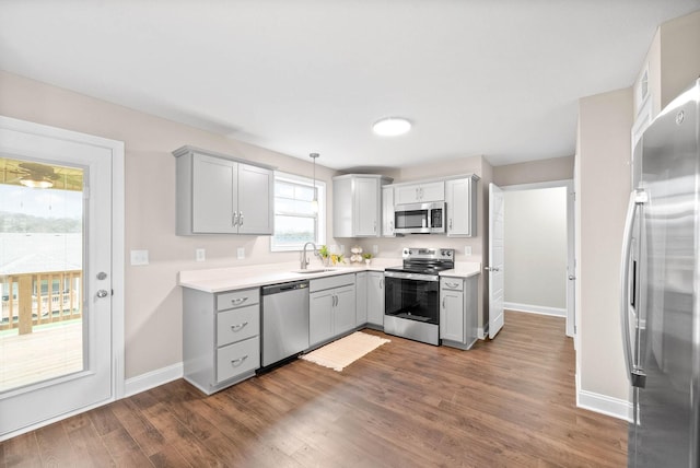 kitchen featuring gray cabinetry, sink, stainless steel appliances, dark hardwood / wood-style floors, and pendant lighting