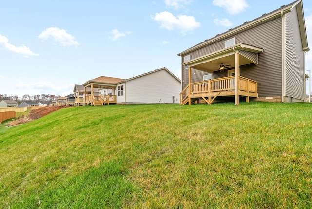 rear view of property featuring ceiling fan, a yard, and a deck