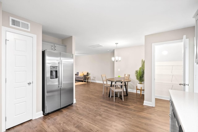 kitchen with a notable chandelier, stainless steel appliances, decorative light fixtures, and hardwood / wood-style flooring