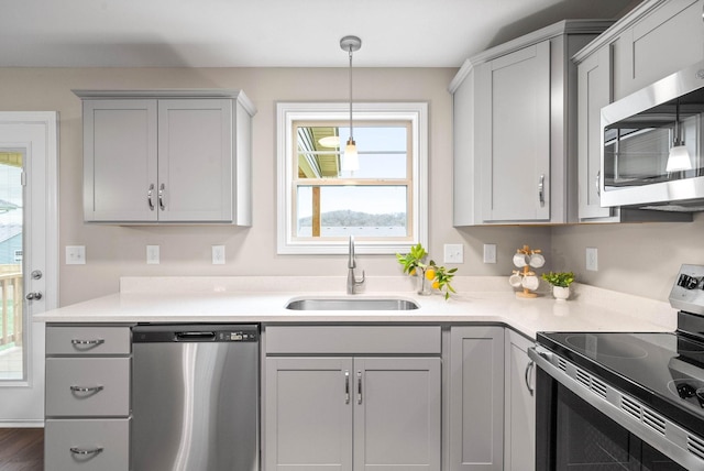 kitchen featuring stainless steel appliances, hanging light fixtures, gray cabinetry, and sink