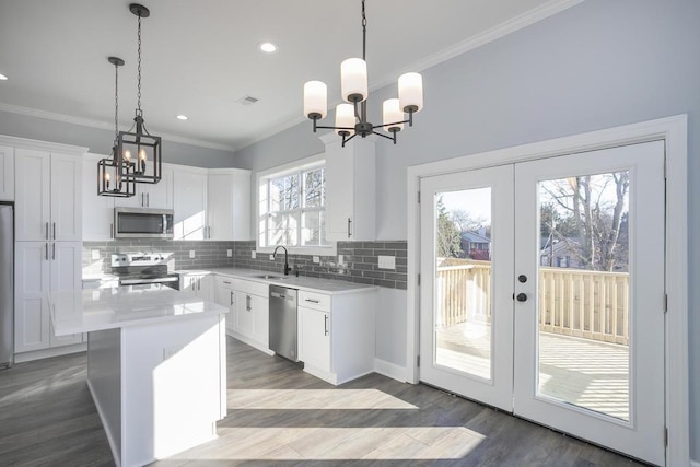 kitchen featuring white cabinets, decorative light fixtures, a kitchen island, and stainless steel appliances