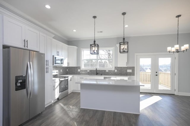 kitchen with white cabinets, decorative light fixtures, stainless steel appliances, and a kitchen island