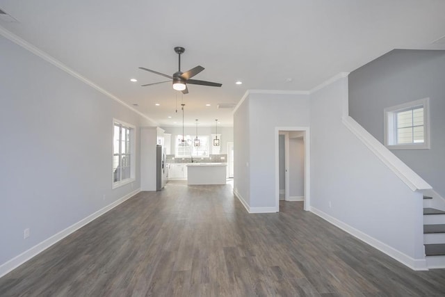 unfurnished living room with crown molding, dark hardwood / wood-style flooring, ceiling fan, and a healthy amount of sunlight