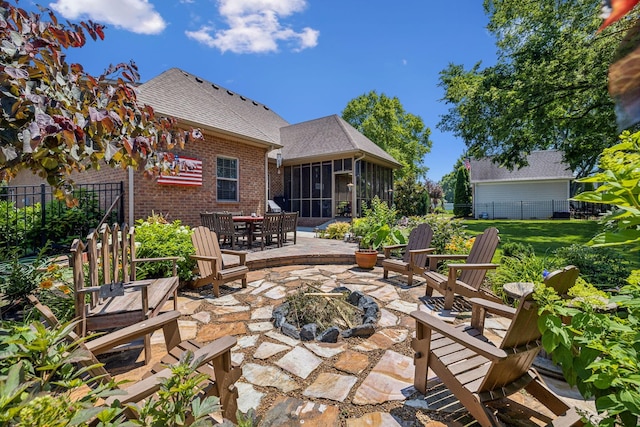 view of patio / terrace featuring an outdoor fire pit and a sunroom