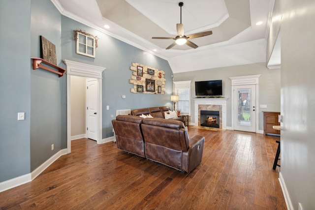 living room featuring a tray ceiling, ceiling fan, crown molding, and dark wood-type flooring