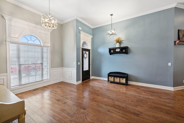 entryway with dark hardwood / wood-style floors, crown molding, and an inviting chandelier