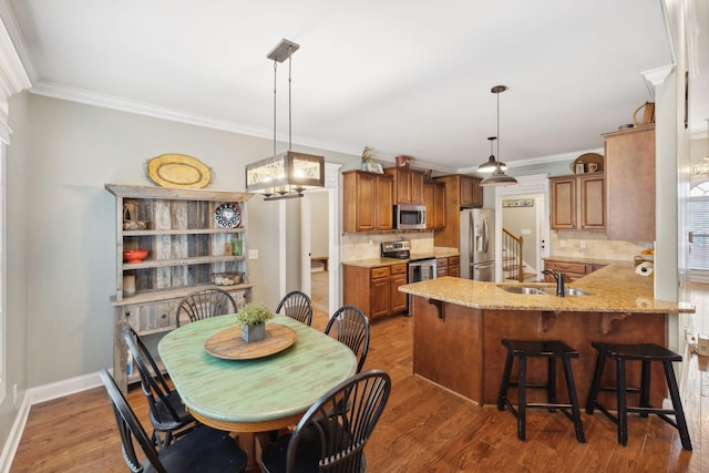 dining room with hardwood / wood-style floors, an inviting chandelier, ornamental molding, and sink