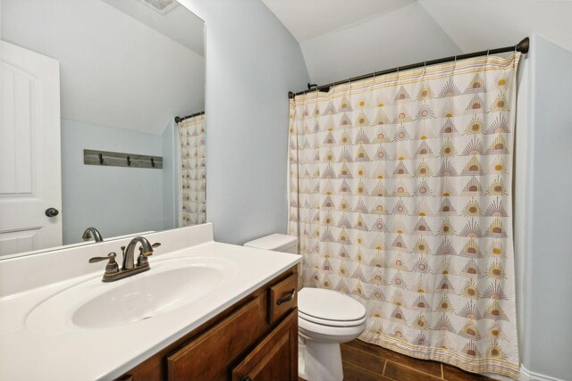 bathroom with toilet, vanity, hardwood / wood-style flooring, and vaulted ceiling