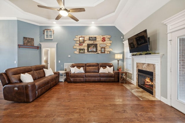 living room featuring hardwood / wood-style flooring, ceiling fan, crown molding, and a tray ceiling