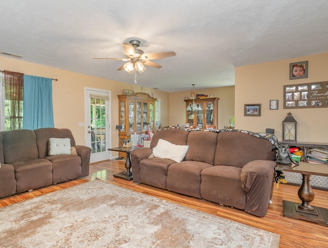 living room with ceiling fan, a textured ceiling, and light wood-type flooring