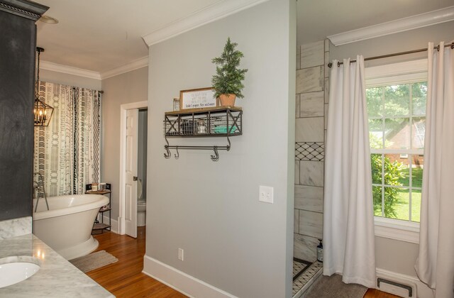 bathroom with plenty of natural light, a washtub, crown molding, and hardwood / wood-style flooring