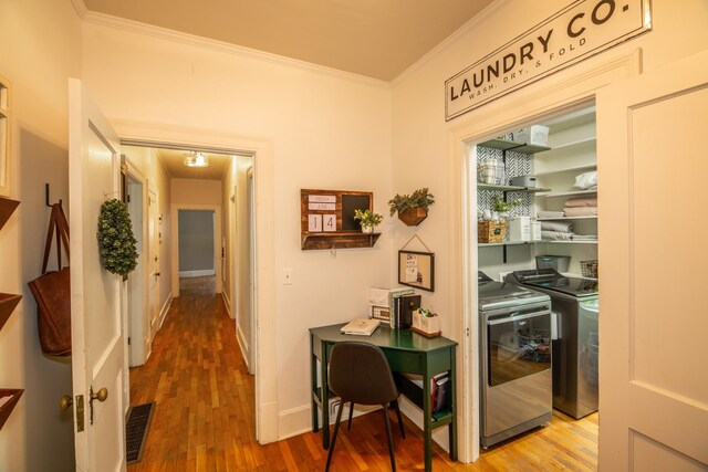 corridor with separate washer and dryer, hardwood / wood-style flooring, and ornamental molding