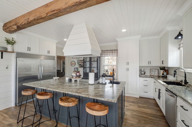 kitchen featuring stainless steel appliances, dark wood-type flooring, a kitchen island, sink, and white cabinetry