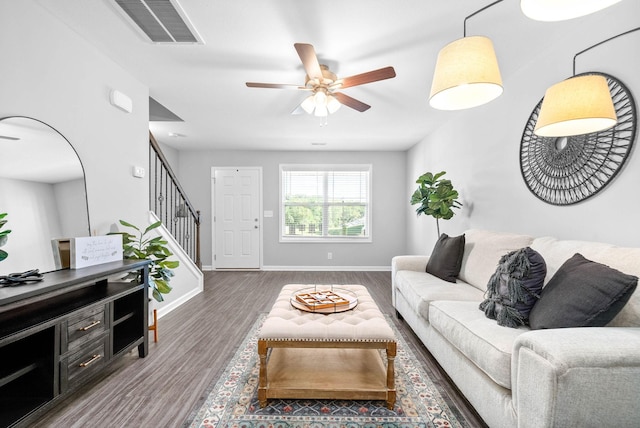 living area with stairway, wood finished floors, visible vents, and baseboards