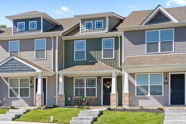 multi unit property featuring a shingled roof, board and batten siding, and a front yard