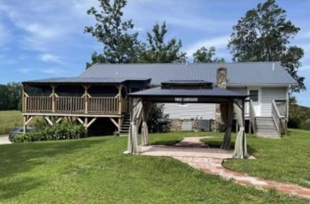 rear view of house featuring a gazebo, a wooden deck, and a lawn