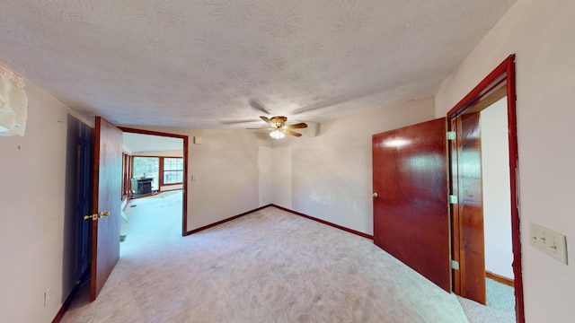 empty room with a textured ceiling, light colored carpet, and ceiling fan