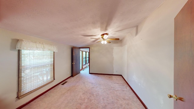 spare room featuring ceiling fan, light colored carpet, and a textured ceiling