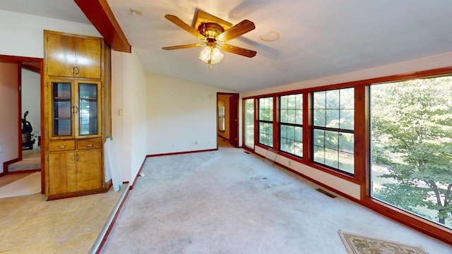 spare room featuring ceiling fan, light carpet, and vaulted ceiling