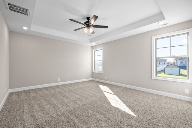 spare room featuring ceiling fan, a tray ceiling, and carpet floors