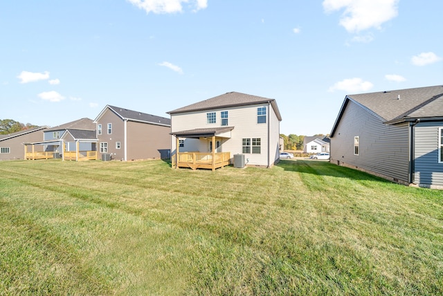 rear view of property featuring central air condition unit, a wooden deck, and a yard