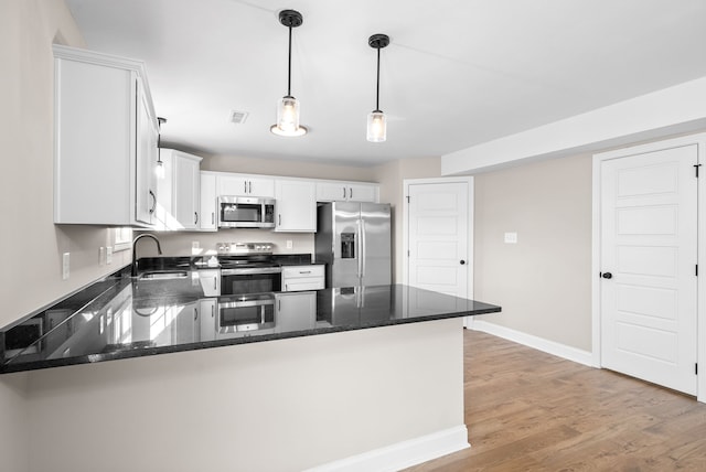 kitchen with kitchen peninsula, sink, white cabinets, light wood-type flooring, and appliances with stainless steel finishes