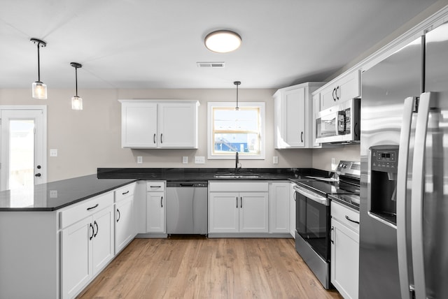 kitchen featuring kitchen peninsula, white cabinets, stainless steel appliances, and decorative light fixtures