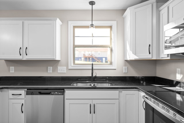 kitchen with stainless steel appliances, dark stone counters, sink, pendant lighting, and white cabinets