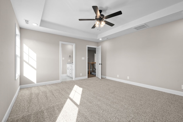 unfurnished bedroom featuring connected bathroom, carpet flooring, a raised ceiling, and ceiling fan