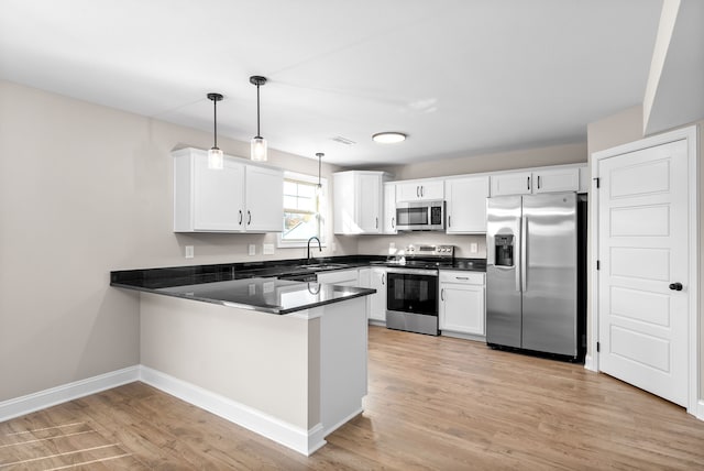 kitchen with white cabinets, kitchen peninsula, stainless steel appliances, and decorative light fixtures