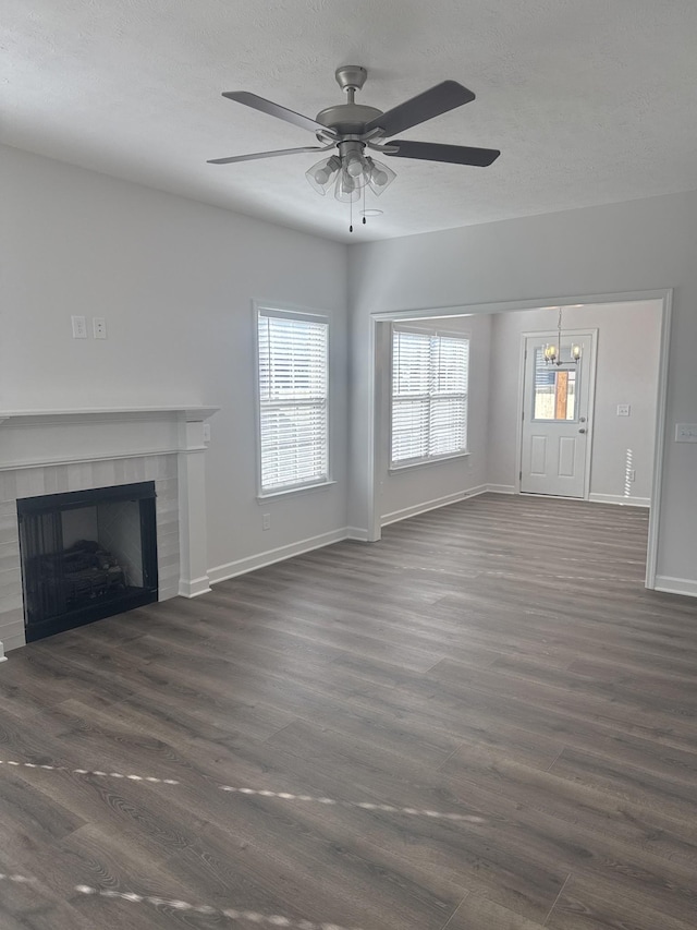 unfurnished living room with dark wood-type flooring, a tiled fireplace, and ceiling fan