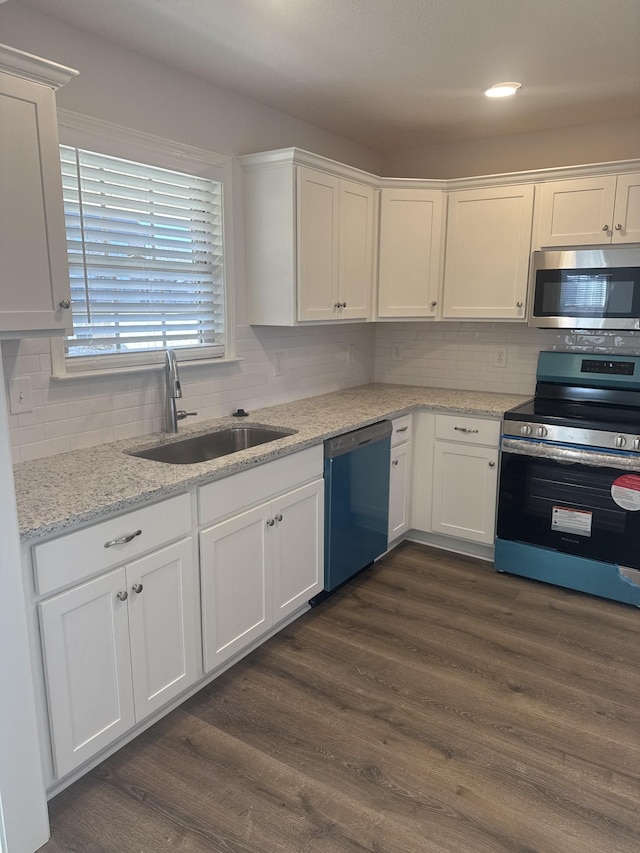 kitchen with appliances with stainless steel finishes, light stone countertops, dark hardwood / wood-style floors, white cabinets, and sink