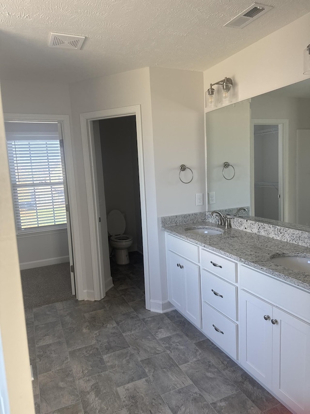 bathroom with toilet, a textured ceiling, and vanity