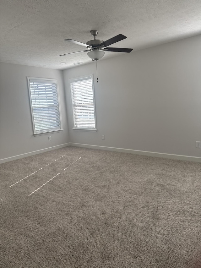 spare room with a textured ceiling, carpet floors, and ceiling fan