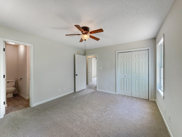 unfurnished bedroom with light carpet, ceiling fan, ensuite bathroom, and a textured ceiling