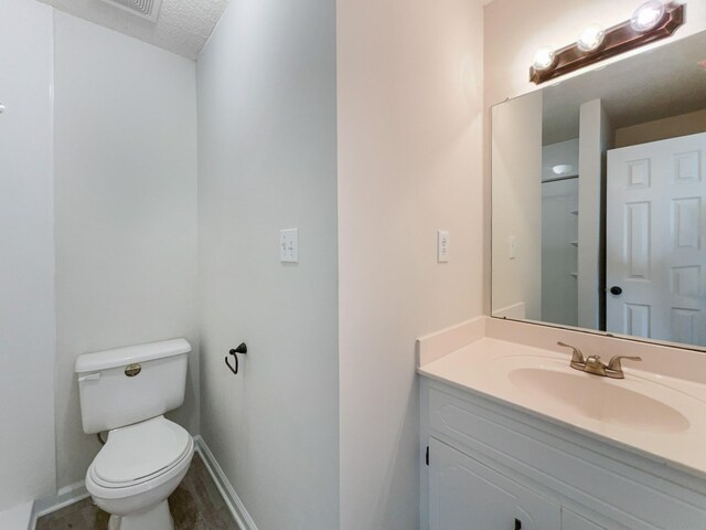 bathroom with vanity, toilet, and a textured ceiling