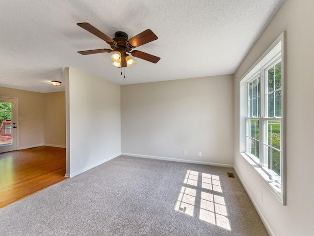 carpeted empty room featuring ceiling fan and a textured ceiling