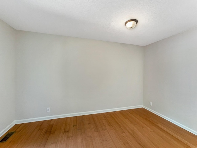 unfurnished room with hardwood / wood-style floors and a textured ceiling