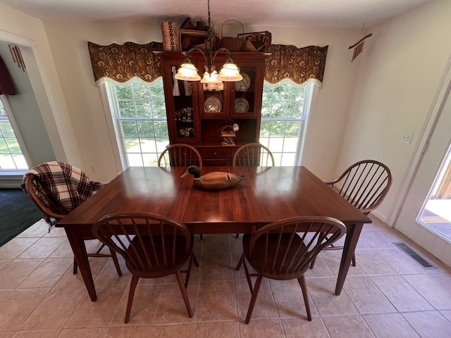 dining area featuring a healthy amount of sunlight, light tile floors, and an inviting chandelier