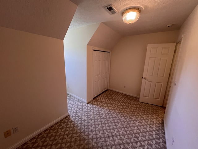 additional living space with a textured ceiling, lofted ceiling, and carpet floors