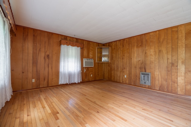 spare room with wooden walls, light wood-type flooring, and a wall mounted AC